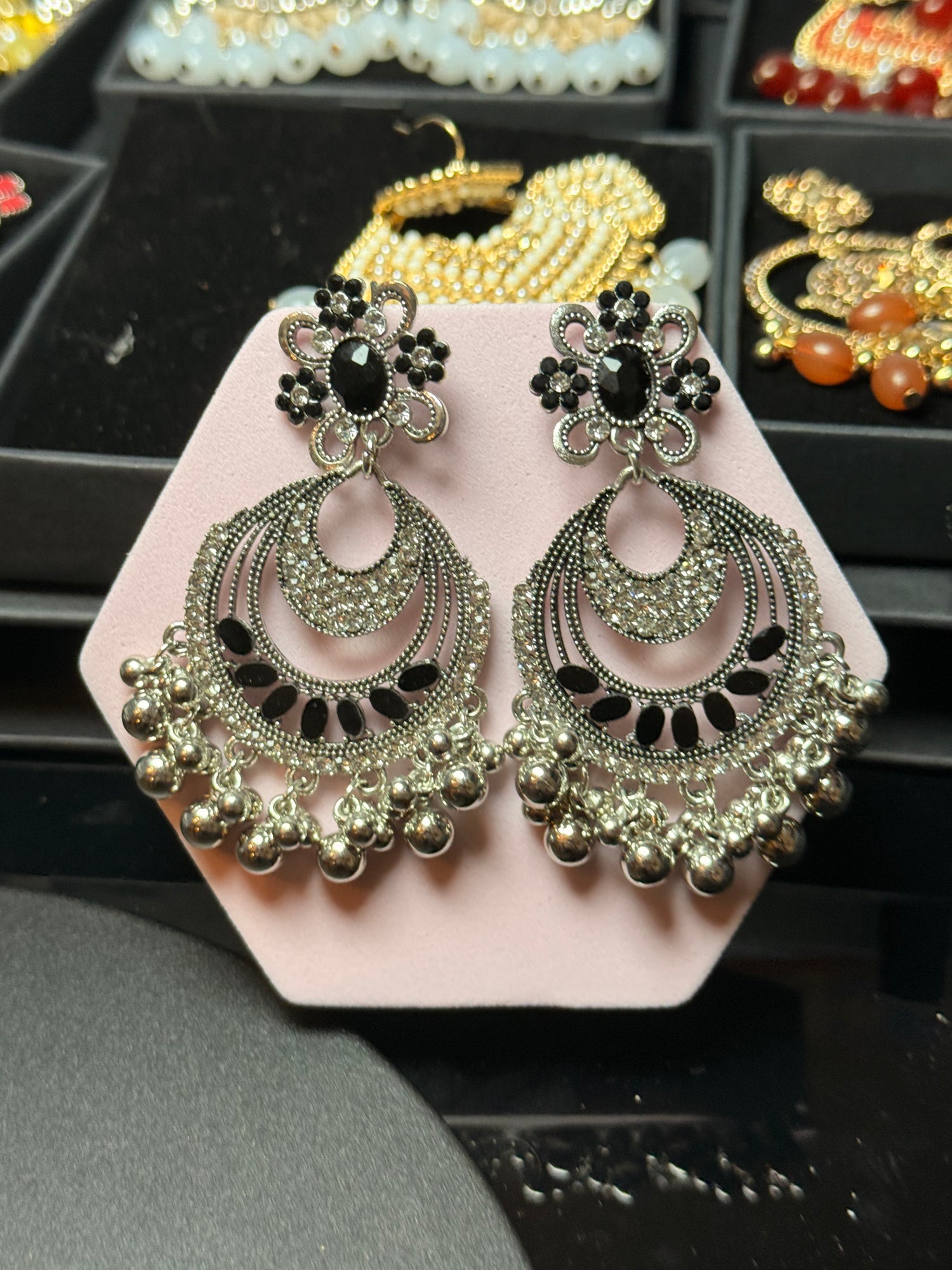Decorative earrings on a pink stand with a blurred background